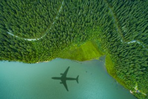 Sustainability image - a aeroplane flies over a blue lake and green forest